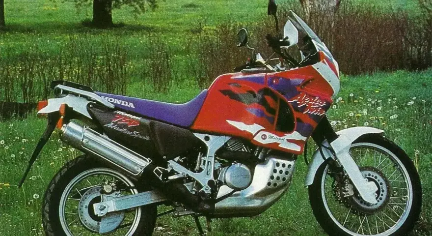Honda Africa Twin 750 Adventure Sports na tle łąki. Choć to legendarny motocykl, warto znać jego wady przed zakupem.