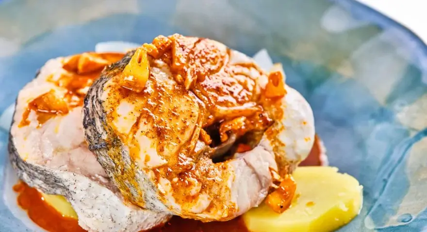 Merluza a la gallega con patatas y salsa de pimentón, un plato tradicional gallego lleno de sabor.