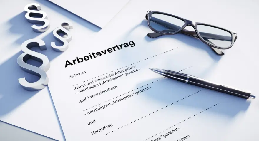 Drei Paragraphen-Symbole, eine Brille und ein Stift liegen auf einem Dokument mit der Überschrift "Arbeitsvertrag". Dies unterstreicht, dass ein Arbeitsvertrag schriftlich sein muss.