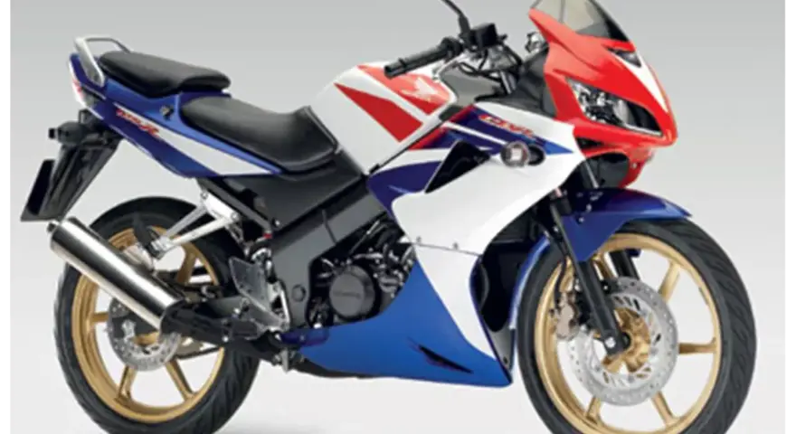 Sportowy motocykl Honda CBR 125R w barwach V-Max, z czerwonym, białym i niebieskim malowaniem.