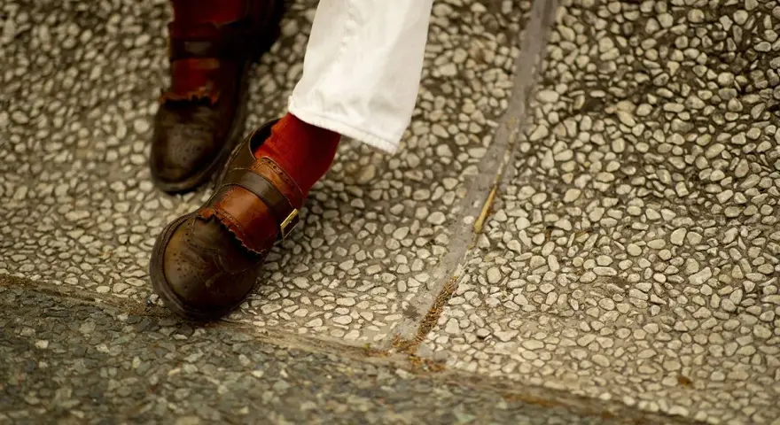 Scarpe marroni uomo con fibbia e calzini rossi, perfette per un look casual chic.