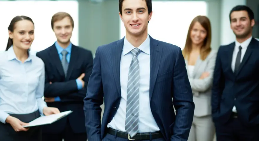 Equipo profesional sonriendo. Un ejemplo de como ir vestida a una entrevista de trabajo: traje oscuro, camisa clara y corbata.