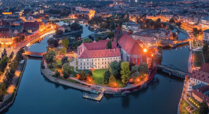 Ostrów Tumski we Wrocławiu nocą, z oświetlonymi budynkami i rzeką. To jedno z najpiękniejszych miejsc Wrocławia.