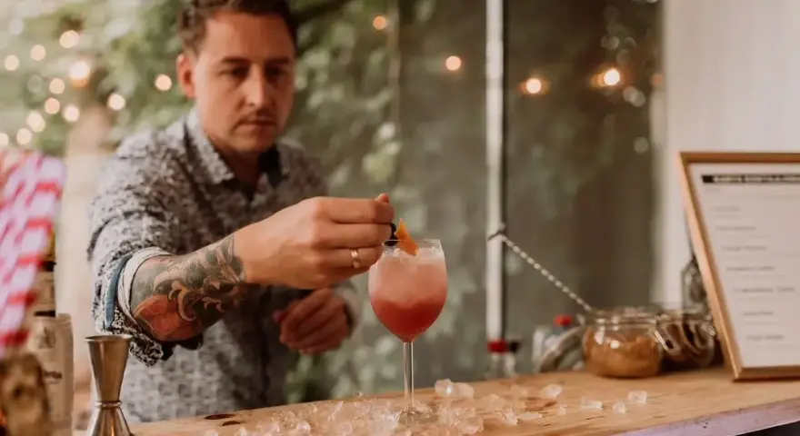Barman z tatuażem na ręce przygotowuje drinka na 18. urodziny. Zastanawiasz się, ile kosztuje barman na 18?