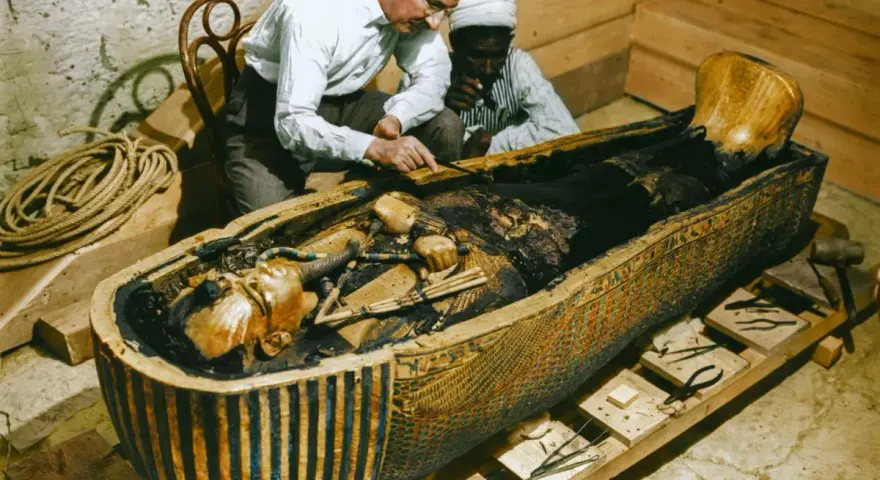 La photo découverte tombeau Toutankhamon : des archéologues examinent la momie dans son sarcophage orné.
