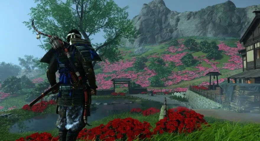 Samuraj w zbroi z łukiem na plecach stoi na tle kwitnącej wiśni. Sceneria z gry Ghost of Tsushima na Xbox.