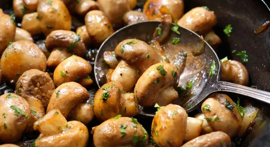 Champiñones salteados con perejil, perfectos para tus recetas con champiñones. Una cuchara sirve para probarlos.