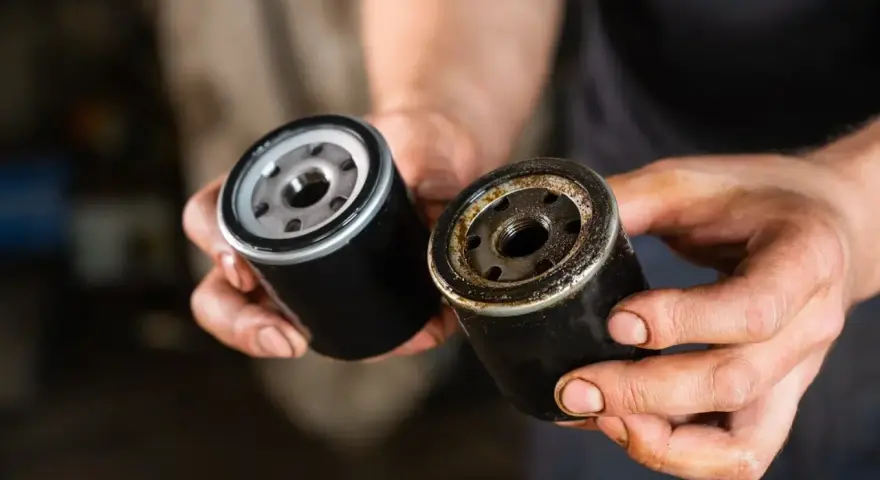 Nowy i zużyty filtr oleju w dłoniach mechanika. Wymiana filtra oleju to kluczowy element dbania o silnik.
