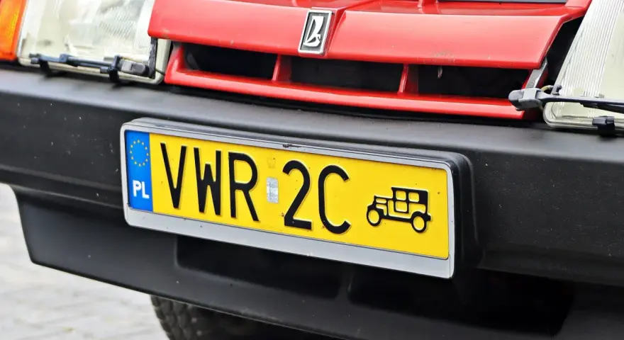Czerwony grill z logo, reflektor i żółta tablica rejestracyjna z napisem VWR 2C oraz symbolem starego samochodu. To jest rejestracja dw.