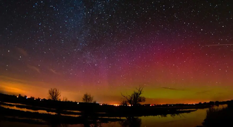 Ein atemberaubendes polarlicht tanzt über einem sternenklaren Himmel, reflektiert in einem ruhigen Gewässer.