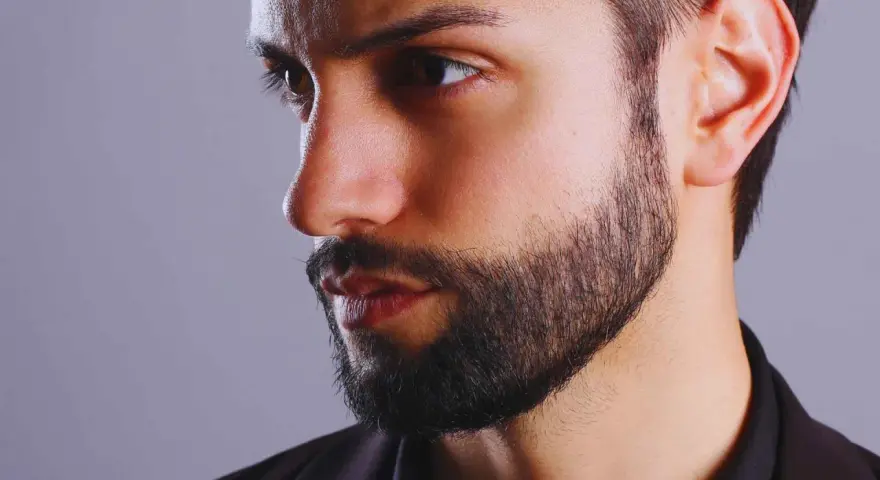 Primer plano de un hombre con barba cuidada, con un estilo fade beard que se difumina hacia las mejillas.