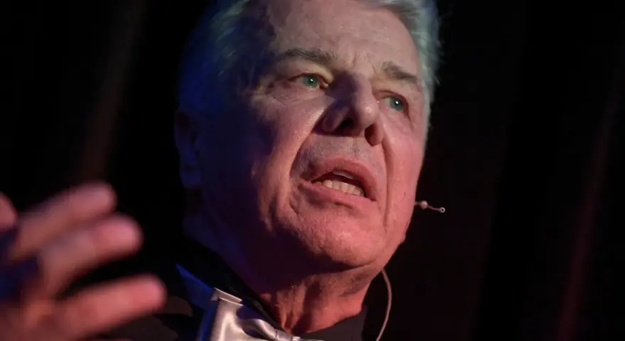 Emilian Kamiński, znany z wielu filmów, w eleganckim stroju z muszką, przemawia na scenie.