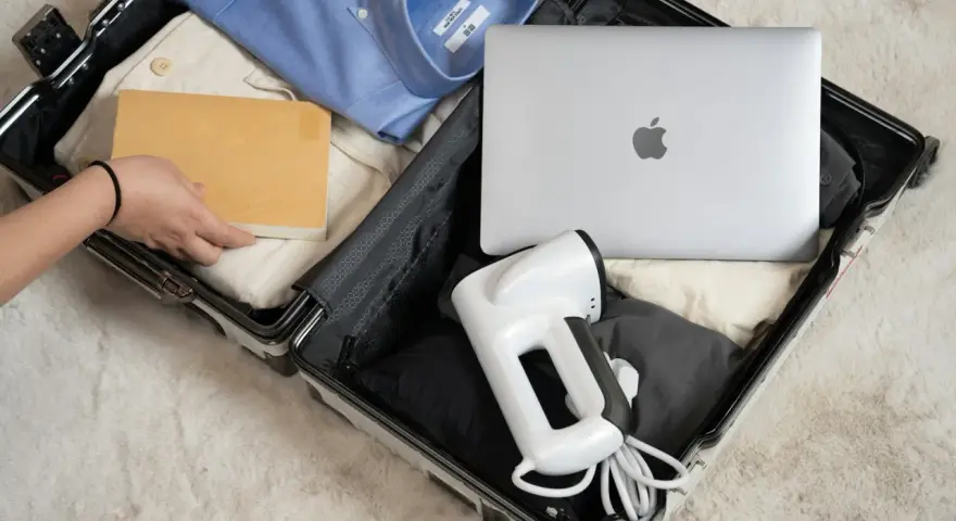 Pakowanie elektroniki w bagażu rejestrowanym: laptop, parownica do ubrań i książka.