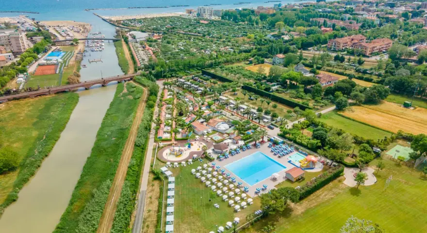 Widok z lotu ptaka na ośrodek campingowy Rubicone z basenami, leżakami, kortami tenisowymi i rzeką w pobliżu morza.