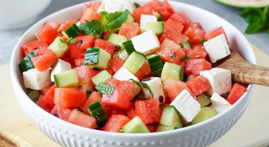 Erfrischender **Salat mit Melone**, Gurke und Feta in einer weißen Schüssel, garniert mit Minze. Perfekt für heiße Tage.