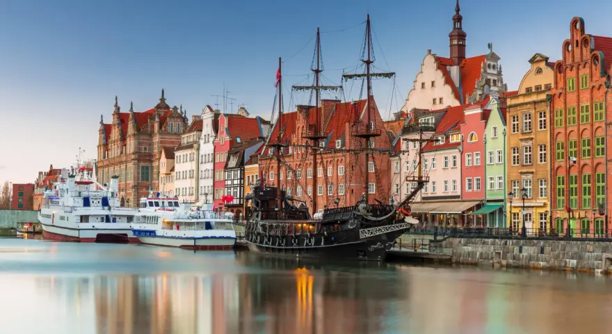 Gdański port z żaglowcem i kolorowymi kamienicami. To miejsce, co warto zwiedzić w Polsce, zachwyca historią i widokami.