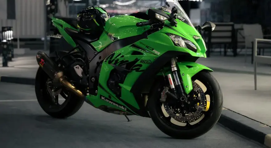 Japoński motocykl Kawasaki Ninja ZX-10R w jaskrawym zielonym kolorze, z kaskiem na siedzeniu, gotowy do nocnej jazdy.