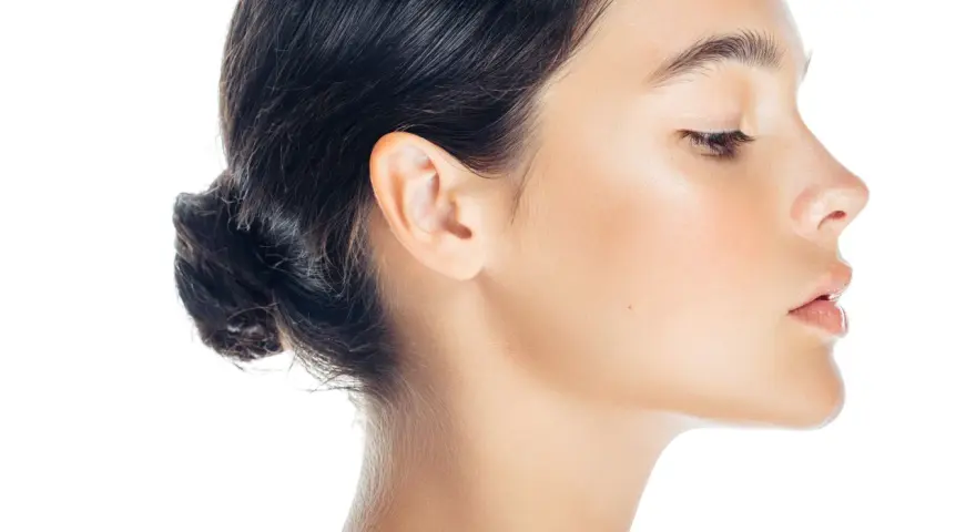 Profilo di donna con trucco leggero, evidenziato il contouring naso per un effetto scolpito. Pelle luminosa e capelli raccolti.