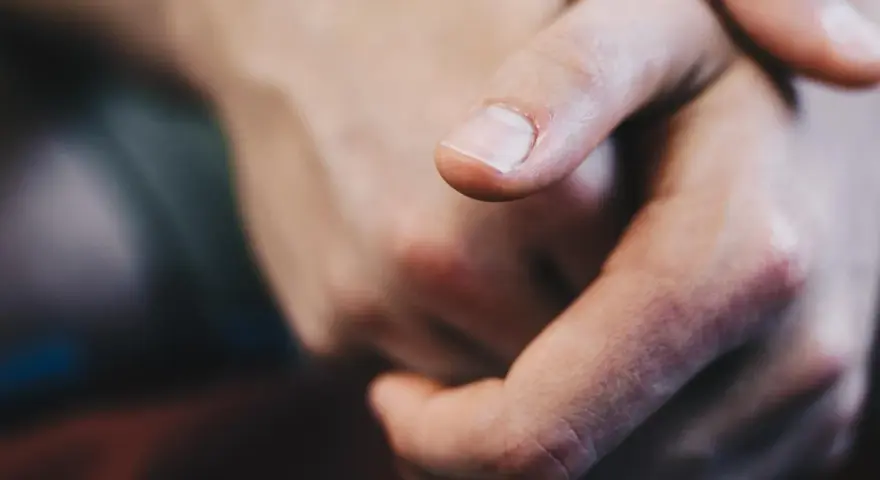 Dita intrecciate, un primo piano che evoca il senso di vibrazione interna e le sue cause, forse ansia o attesa.