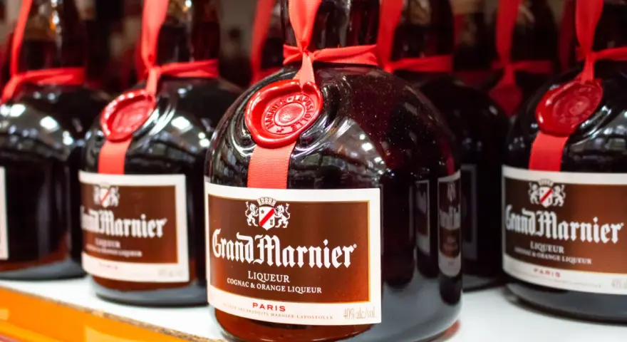 Butelki likieru Grand Marnier, idealnego do margarity. Czerwona wstążka i pieczęć dodają elegancji.