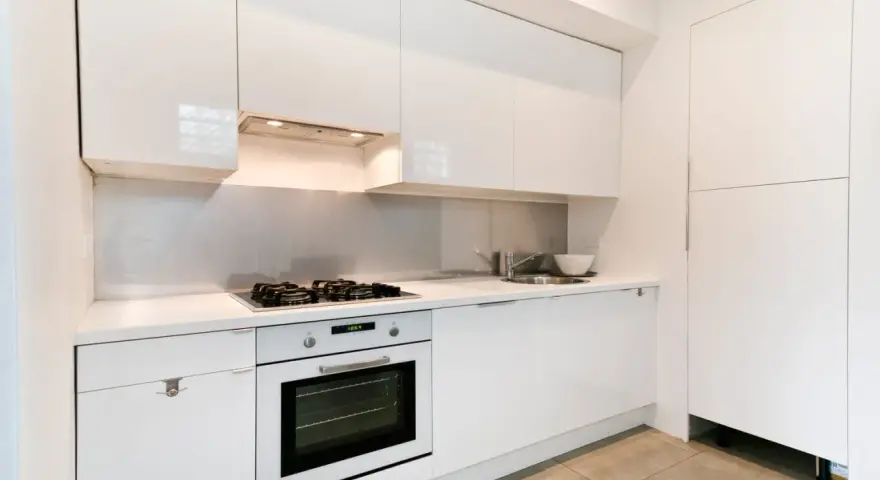 Cuisine moderne blanche avec hotte intégrée au-dessus de la plaque de cuisson. La hauteur de la hotte cuisine est idéale pour une utilisation confortable.