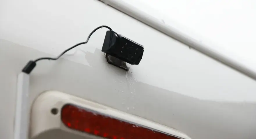 En liten svart backkamera monterad på en vit yta, redo att installera för bättre sikt bakåt.