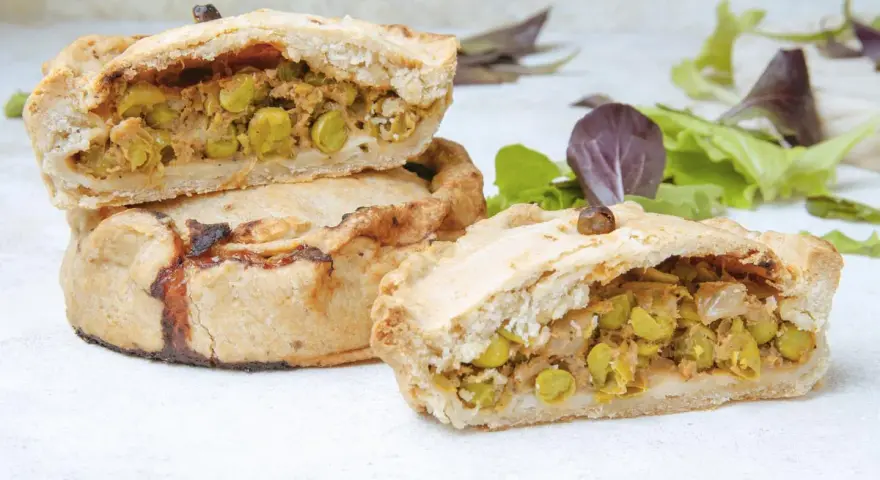 Panades mallorquinas cortadas, mostrando el relleno de guisantes y carne.