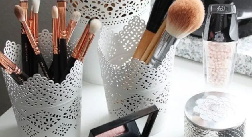 Des pinceaux de maquillage et des produits de beauté dans des pots ajourés. Une belle organisation pour le recyclage du maquillage.