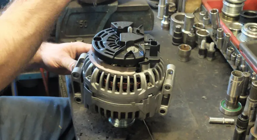 Warsztat samochodowy. Mechanik pracuje nad regeneracją alternatora. Sprawdź, jaka jest regeneracja alternatora cena.