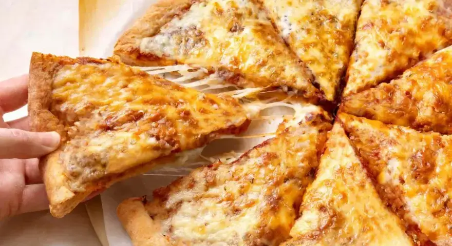 Pyszne, gorące ciasto na pizzę z ciągnącym się serem, które właśnie jest podnoszone.