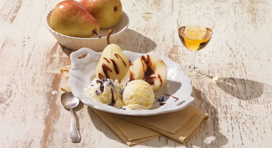 Gegarte Birnen mit Schokoladensauce und cremigem Vanilleeis, garniert mit Lavendelblüten. Ein köstliches Birnen Eis Dessert.