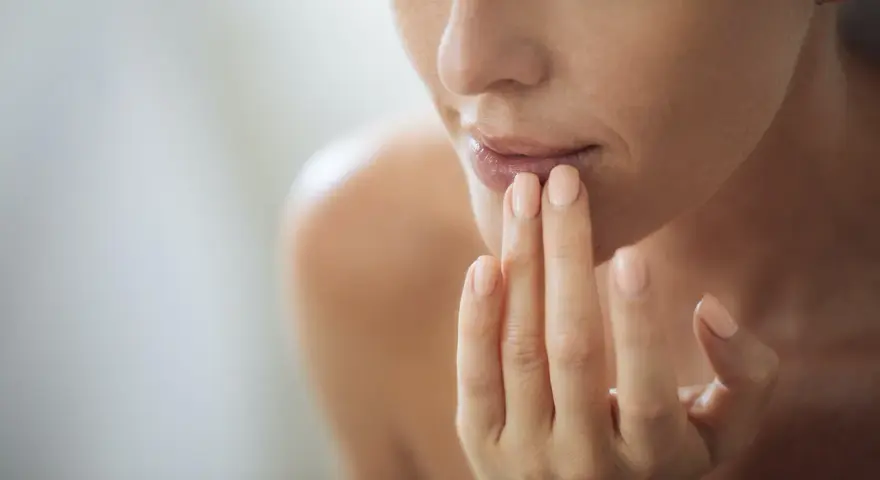Nahaufnahme einer Frau, die sich mit den Fingern die Lippen berührt. Ein sanfter Blick auf natürliche Schönheit, vielleicht inspiriert von hausmittel gegen falten.