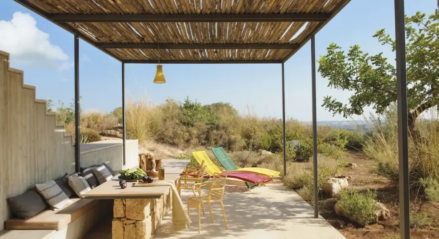 Porches sencillos y bonitos con mesa de piedra, asientos cómodos y tumbonas bajo un techo de madera.