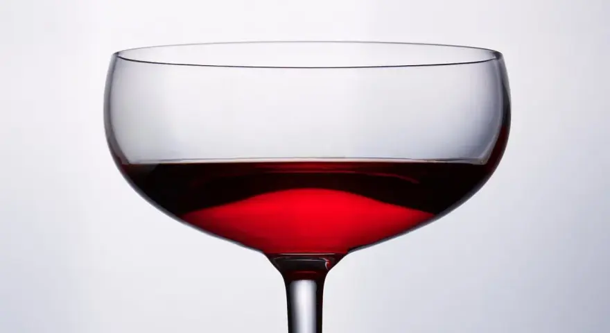 Cachaca co to? Kieliszek z czerwonym, przejrzystym płynem, który może być cachacą, na jasnym tle.