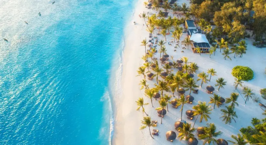 Rajska plaża na Zanzibarze z turkusową wodą, białym piaskiem, palmami i luksusowym resortem. Idealne miejsce, kiedy na Zanzibar.