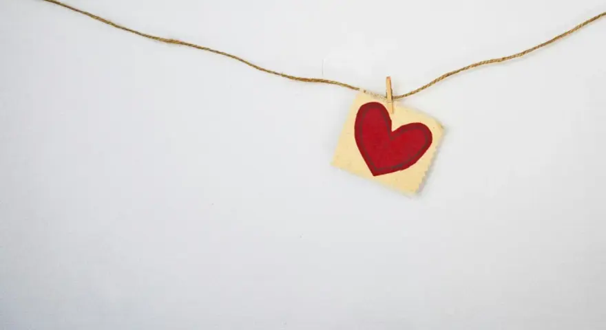 A red heart on a small fabric square, hung by a clothespin on a string. A simple symbol, asking: does God love everyone?
