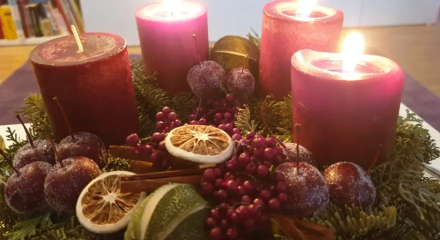 Adventskranz mit vier roten Kerzen, Tannenzweigen, Beeren, getrockneten Früchten und kleinen Äpfeln. Der 6. Sonntag nach Ostern ist noch weit, aber die Vorfreude auf Weihnachten ist spürbar.