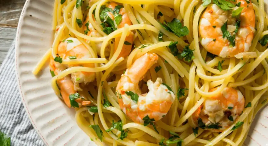 Un piatto invitante di pasta con gamberetti, condita con prezzemolo fresco e un filo d'olio.
