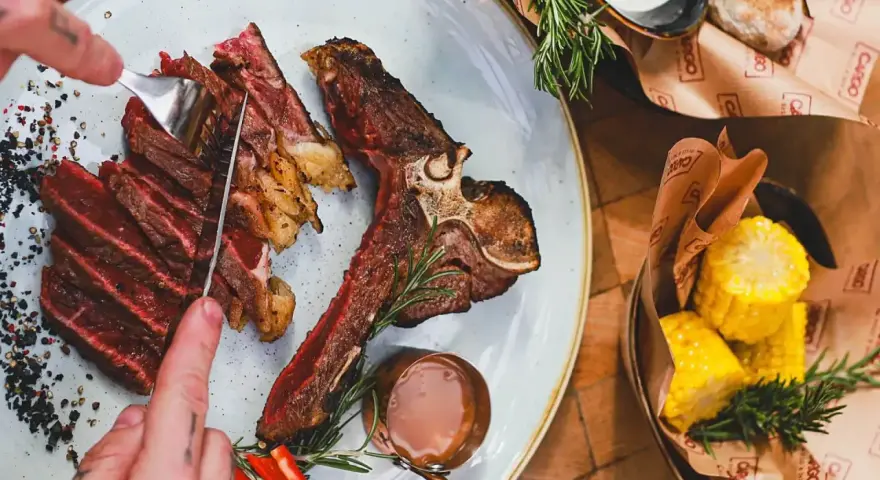 Idealne jakie wino do steka? Soczysty stek T-bone z pieczonymi kolbami kukurydzy i sosem.