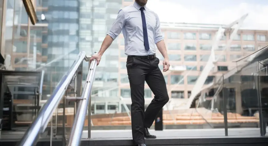 Uomo con pantaloni neri come abbinarli: camicia azzurra e cravatta blu, un look da ufficio moderno.