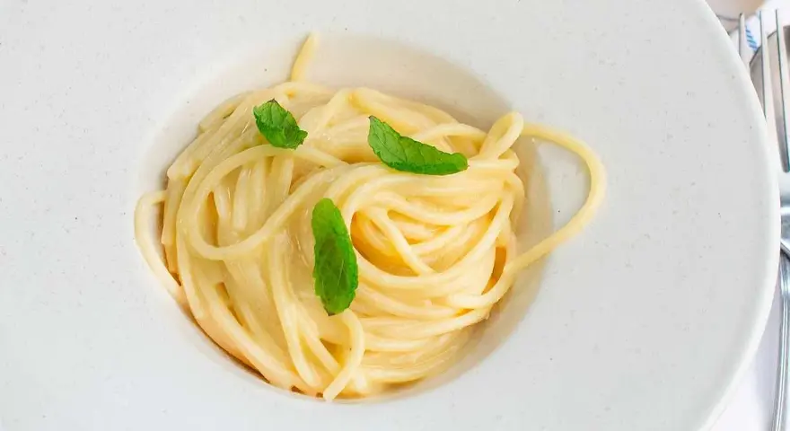 En krämig pasta limone, serverad i en vit skål med färska myntablad.