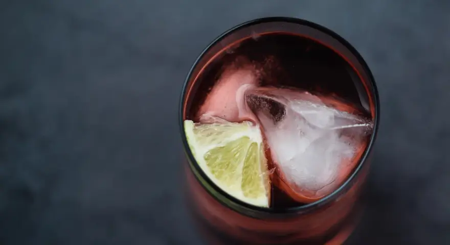 Czerwony drink z lodem i limonką. Idealny do degustacji z brandy Kazbek Peak, odkryj nowe smaki!