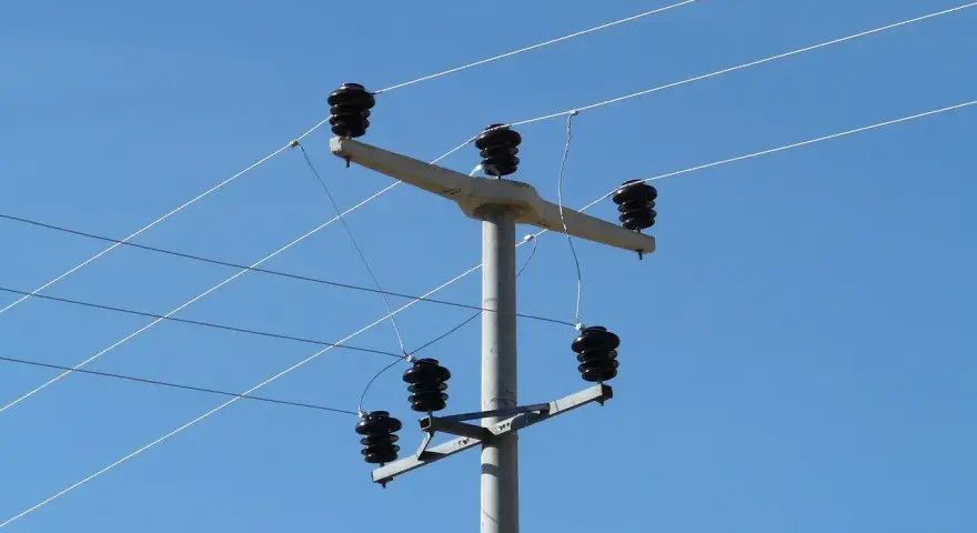 Słup energetyczny z izolatorami, na którym widać przewody elektryczne. Taryfa B23 może być związana z takim właśnie zasilaniem.