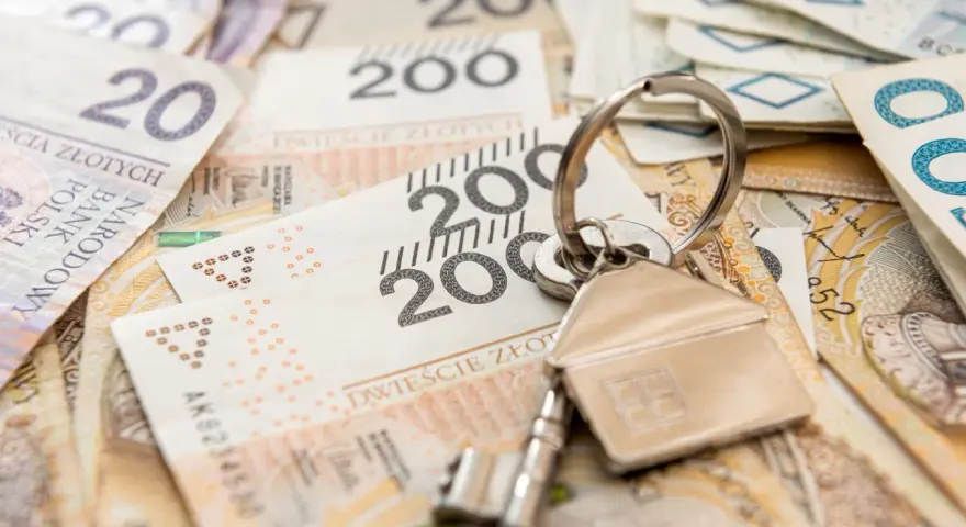 Klucze do domu na stosie polskich banknotów. Może to symbolizuje spłatę kredytu hipotecznego lub inwestycję, a może nawet windykację Santander.