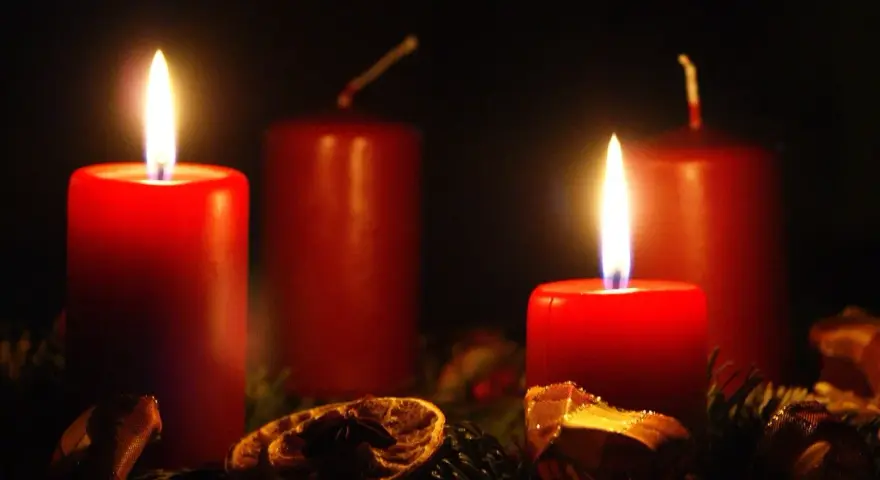 Two red candles glow, marking the 2nd advent. A festive wreath with dried orange slices and pine needles surrounds them.
