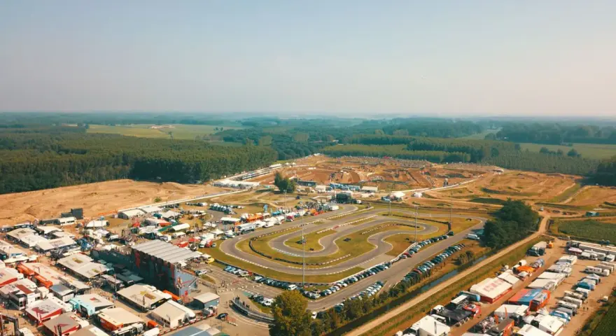 Vista aerea di un circuito **ottobiano motorsport** con paddock, tribune e pista da cross sullo sfondo, immerso nel verde.