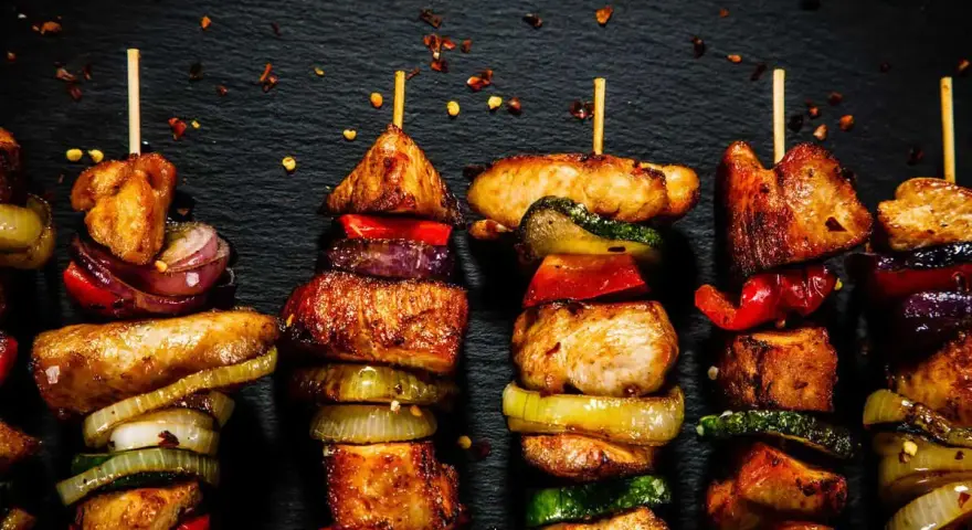 Spiedini di carne succulenti e colorati, alternati a cipolle, peperoni e zucchine, pronti per essere gustati.