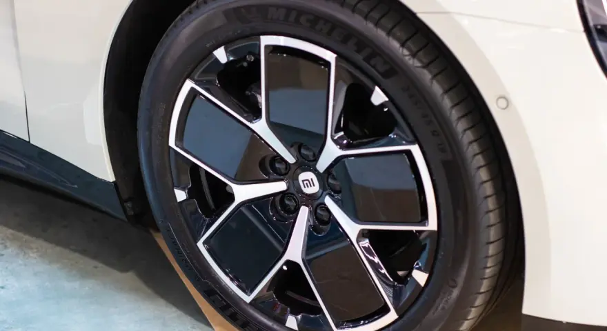 Pneu Michelin sur jante noire et argentée avec logo Mi sur une voiture blanche.