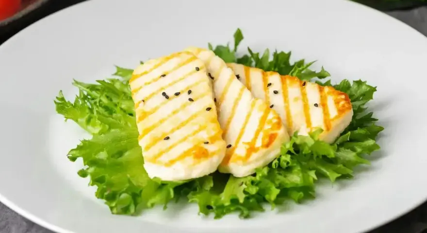 Grillowany ser halloumi na sałacie, posypany czarnuszką. Czy ser halloumi jest zdrowy? To pyszna przekąska.