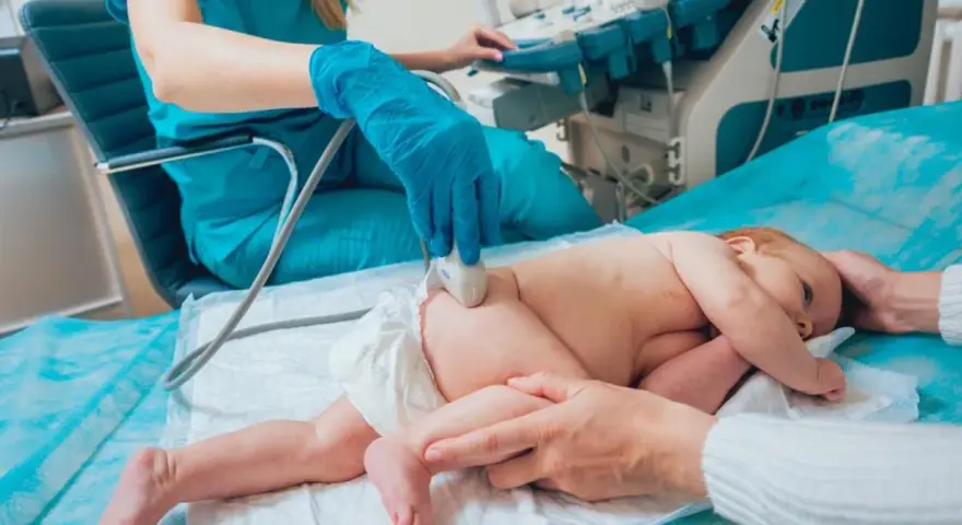 Lekarz wykonuje USG bioderka u niemowlaka. Badanie jest ważne dla prawidłowego rozwoju malucha.